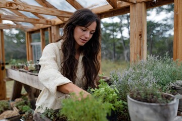 Young caucasian female gardening in a greenhouse with potted plants