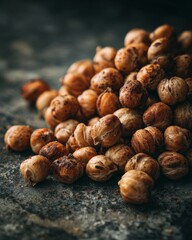 Obraz premium Roasted Brown Nuts Piled on Dark Stone Surface with Shallow Depth of Field for Culinary and Food Photography Use