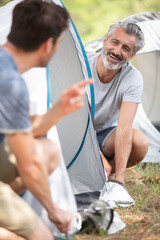 Obraz premium senior man and son building tent at campsite