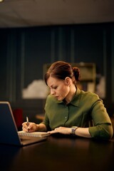 Professional Woman Focusing on Work with Notebook and Laptop in Office Setting