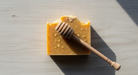 Handcrafted honey soap bar with a wooden honey dipper on a rustic light wood surface, showcasing natural skincare and artisanal products.