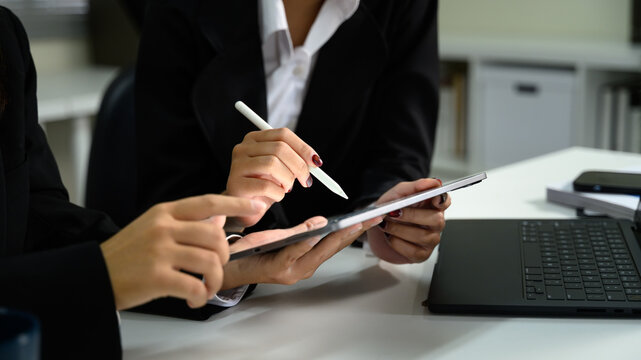 Close up of business professionals collaborating on digital tablet with stylus in office