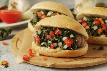 Choripan - bread with grilled sausages with chimichurri sauce, traditional Argentinian fast food dish	