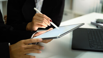Coworkers analyzing data on digital tablet for corporate planning
