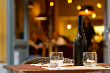 Table with bottle and glasses against defocused cozy restaurant view