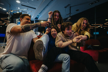 Friends laughing and having fun while playing a video game indoors, highlighting social gatherings and friendly competition.