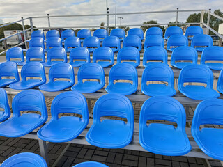 Rows of empty bright blue plastic seats in a stadium. Sports, audience, and event concept. Seating for spectators.