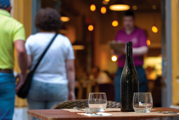 Outside restaurant table against defocused elderly couple standing at the doorway about to come in