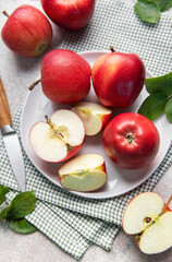 Fresh red apples whole and sliced on white plate with green leaves