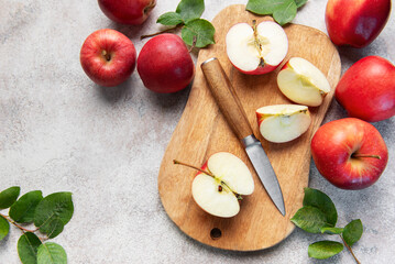 Fresh red apples and slices with knife on wooden cutting board