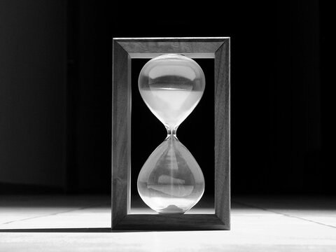Vintage Sand Glass With Flowing Sand Illuminated In Darkness Grayscale Stock Image 
