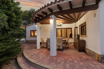 Evening view of the Mediterranean-style terrace with illuminated windows and garden features.