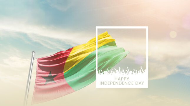 Guinea-Bissau flag waving proudly under a bright sky with text happy independence day. Guinea-Bissau national flag for independence day.