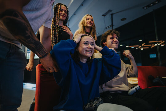 A group of young friends engaging in a lively video game contest, expressing joy and excitement in a modern, cozy living space.