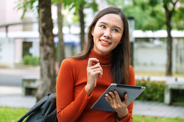 woman in orange sweater is holding  tablet in her hand