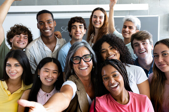 Happy teacher and multiethnic students taking selfie in classroom