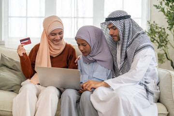Muslim family using laptop for online shopping and holding credit card, islamic digital lifestyle and modern islamic banking, e-commerce trends, halal marketplace and islamic finance family planning