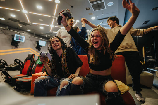 Group of enthusiastic friends playing video games in a vibrant gaming lounge, celebrating their victory with joy and excitement. A scene showcasing fun, technology, and strong social connections.