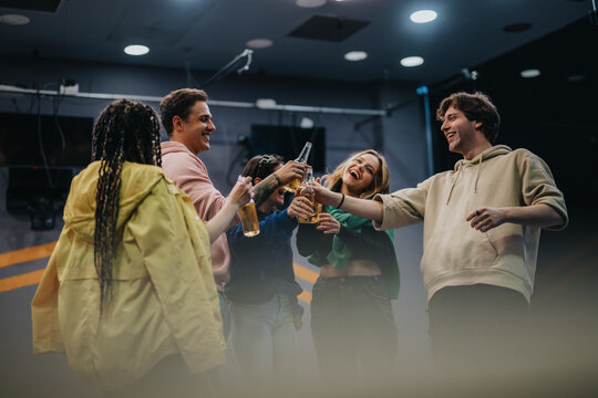 Group of friends sharing joyful moments, raising bottles to toast while enjoying an uplifting time in a casual indoor setting.