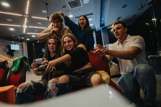 Fototapeta group of friends gathering for an intense and fun-filled gaming session, sharing moments of joy and excitement. The setting is modern with dynamic lighting, showcasing youthful friendship and leisure.