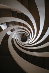 Fototapeta premium Top-down view into spiral staircase forming graphic vortex