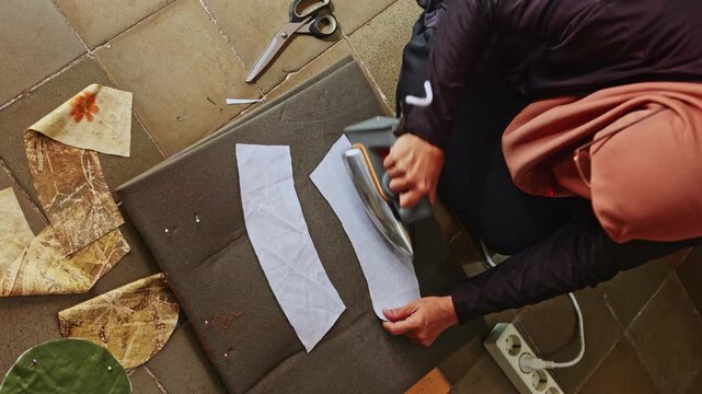 Muslim seamstress ironing fabric at home workshop