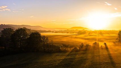Radiant Morning Sunlight Over Rural Landscape With Misty Fields