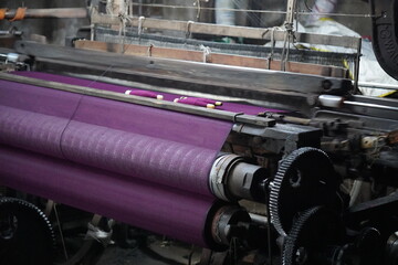 Industrial powerloom machine with multiple fabric rolls in textile manufacturing factory