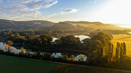 Sunlit River Bend Surrounded by Autumn Trees and Hillside Village