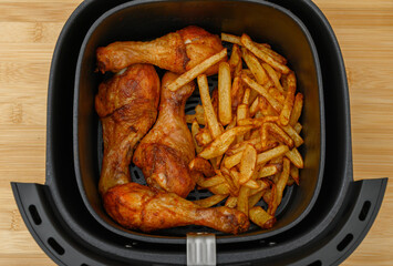 Crispy chicken drumsticks and fries fried without fat in an air fryer