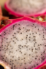 ripe red pitaya cut in half with small black seeds and white soft sweet flesh inside, sweet ripe dragon fruit with black small seeds and light flesh cut in half