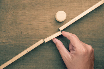 The last piece is placed as the round wooden object successfully crosses the gap, symbolizing successful execution, goal achievement, and progress through teamwork