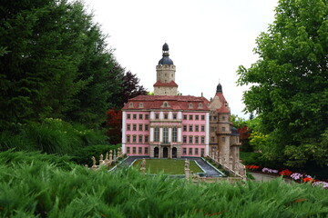 Old European building facade with open windows decorated with bright red geraniums in flower boxes.