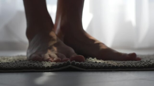 An adult man stands on a clean bath mat.
The man's bare feet are large.
A man stands on a bath mat in a shower room.