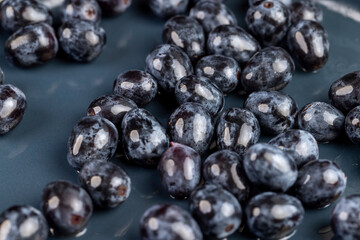 a beautiful ripe blue grape, torn from a branch, lying on a bowl, covered with drops of water, wet fruits of pure blue grapes on a blue bowl during cooking