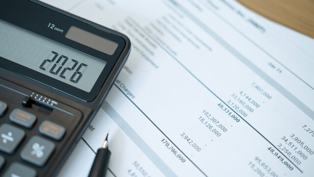 Close up of black calculator screen showing 2026 with detailed financial reports underneath. This composition highlights data analysis and preparation for upcoming financial decisions.