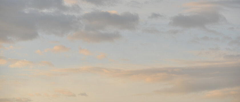 Multiple nuages dans un ciel ros&eacute;, bleu et gris au lever du soleil, format banni&egrave;re