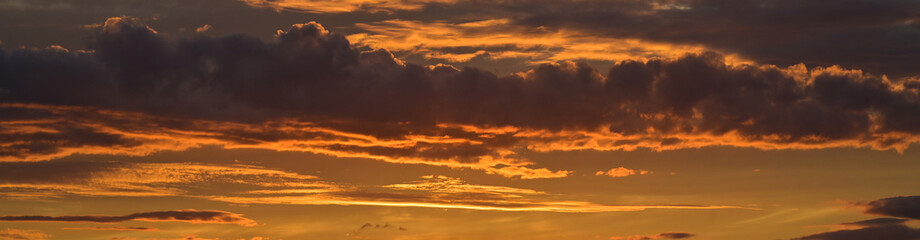 Panorama d'un ciel orange et nuages de type cumulus au coucher du soleil