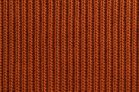 Close-up of orange knitted wool fabric with vertical ribbed pattern. Warm textured background for fashion, handmade crafts, cozy winter clothing and interior design