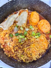 Spicy ramen stew soup with dumplings and fish cake in a bowl
