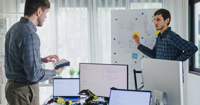 Team adult male engineer develop present AI robotics hand project at tech workspace. Artificial intelligence, collaboration support prototype development, robotic, debugging, machine learn, training.