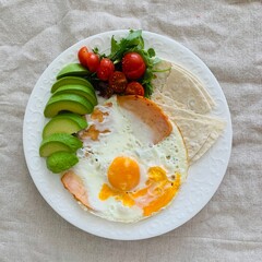 Fried eggs with avocado and vegetables
