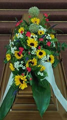 Blumengesteck mit Sonnenblumen auf Sarg