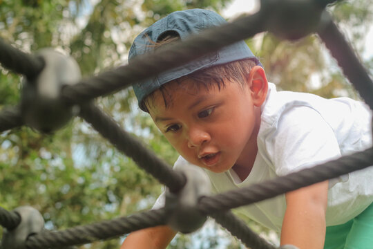 Little boy climbing rope at playground
