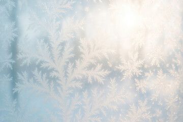 Delicate frost patterns on window with soft sunrise light creating a serene winter atmosphere