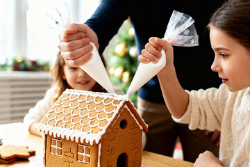 Family decorating gingerbread house together for festive holiday activity and creative fun