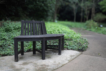 緑のぼけた背景、濃い茶色の円形のベンチ