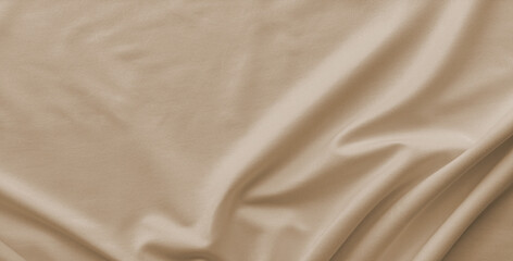Close-up soft warm beige or tan fabric with flowing curves and drapes. The material has subtle sheen and fine, visible texture. Soft shadows and highlights emphasize smooth folds and ripples