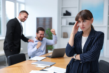 Fototapeta premium Woman feeling jealous of her colleague's success in office, selective focus