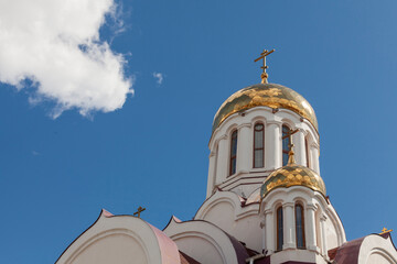 The golden domes of a white-stone Orthodox church against a blue sky